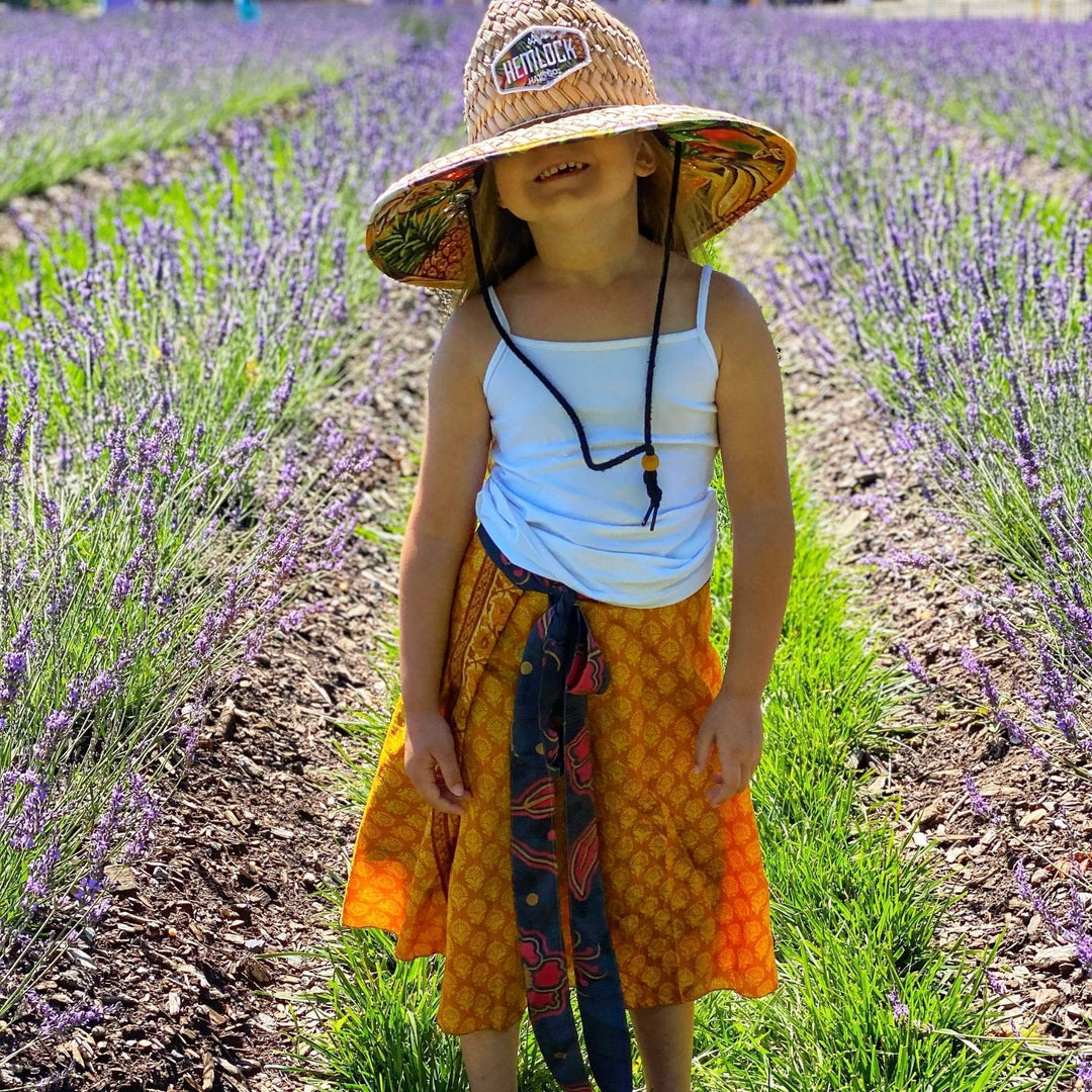 Kid model is outside wearing a one of a kind orange sari wrap skirt.