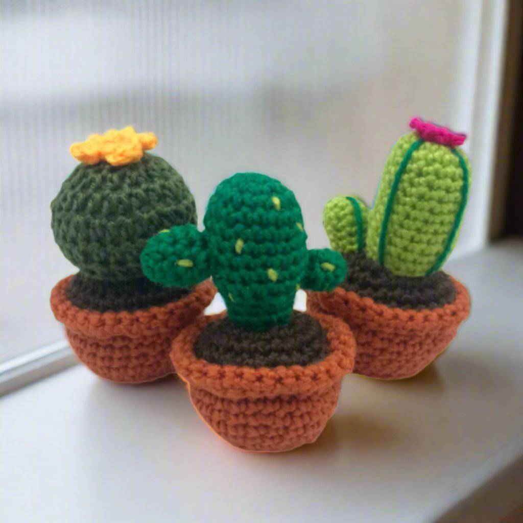 3 knit cacti amigurumis in knit terra cotta pots on a white background