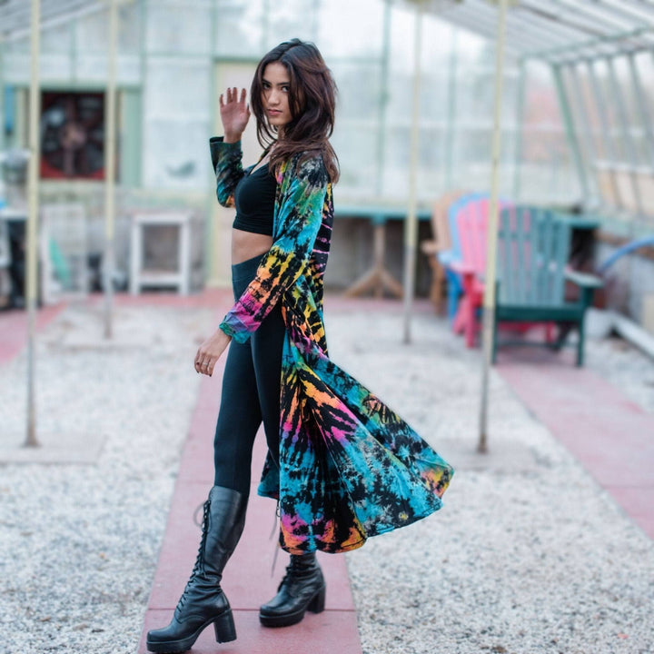 Woman in a tie-dye duster walking through a greenhouse.