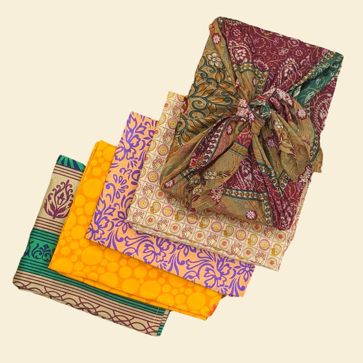 5 assorted packages of furoshiki gift wrap on a light yellow backdrop. 