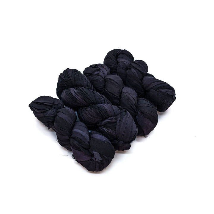 4 skeins of black ribbon yarn on a white background