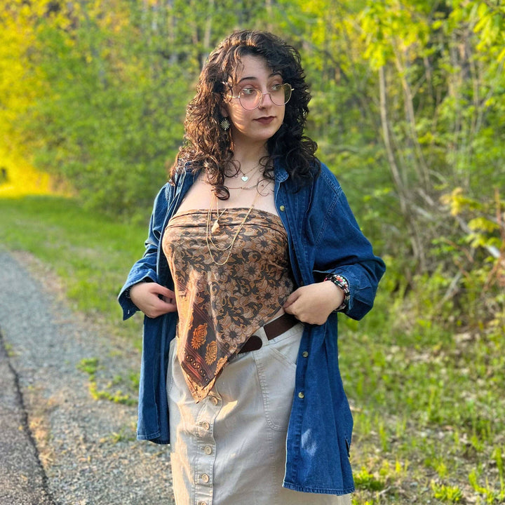 A woman wearing glsases posing wearing ella sari scarf top.