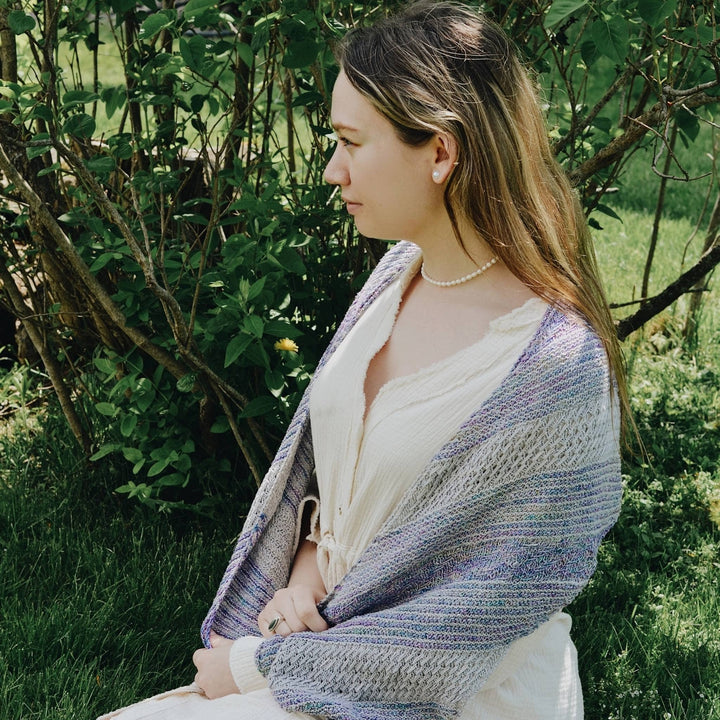 model wearing frosted forest wrap (white and light blue) with greenery in the background.