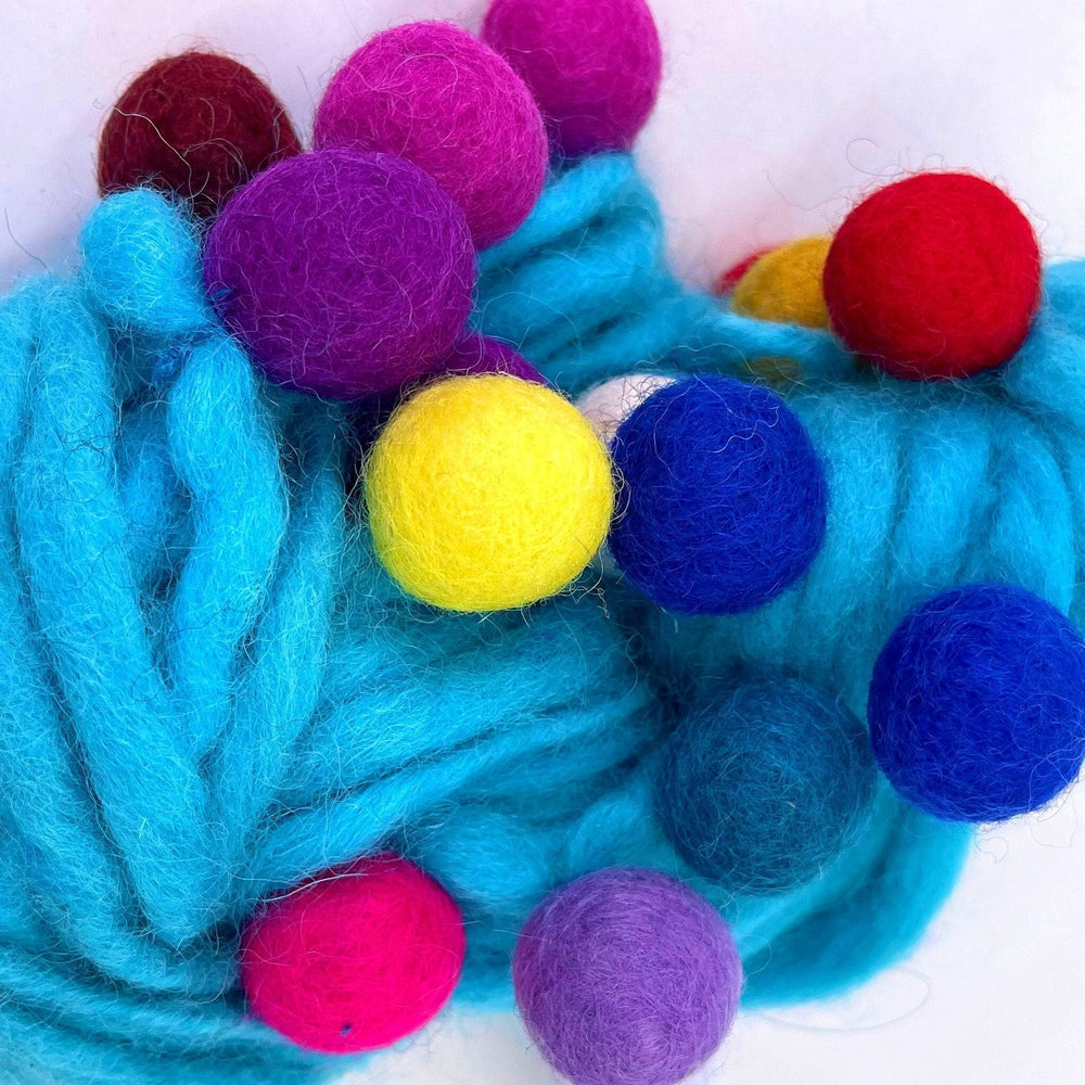 Bright blue yarn with colorful felted wool balls in vibrant shades.