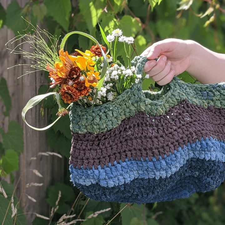 a cool toned colored bag being held outside