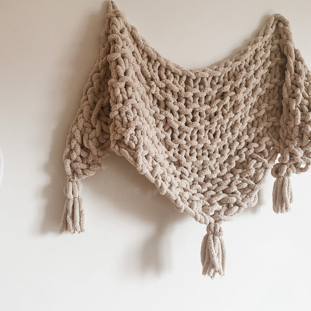 Beige knitted shawl with tassels on a white background