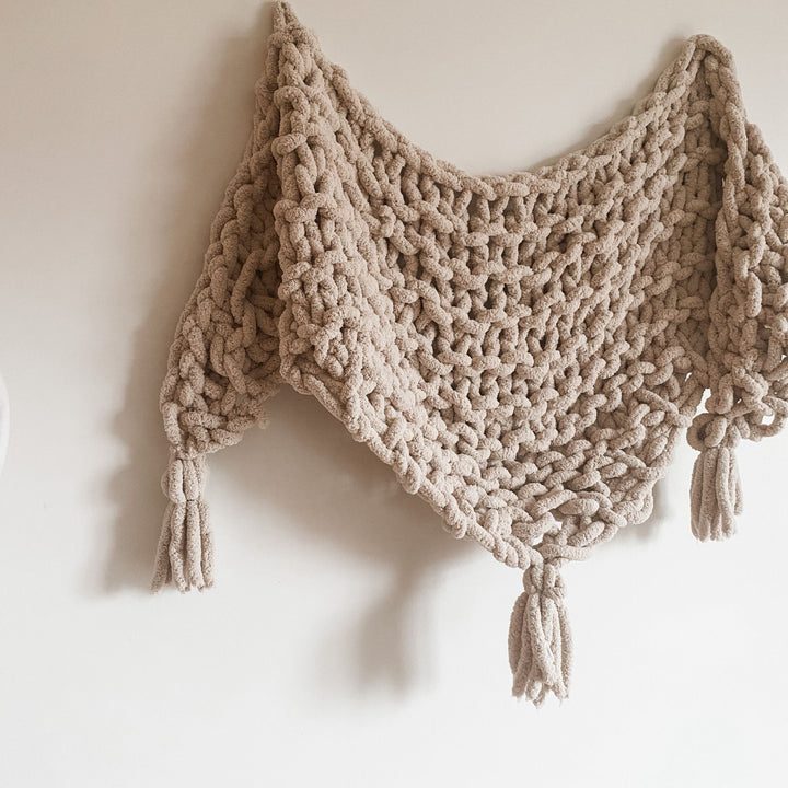 Beige knitted shawl with tassels on a white background