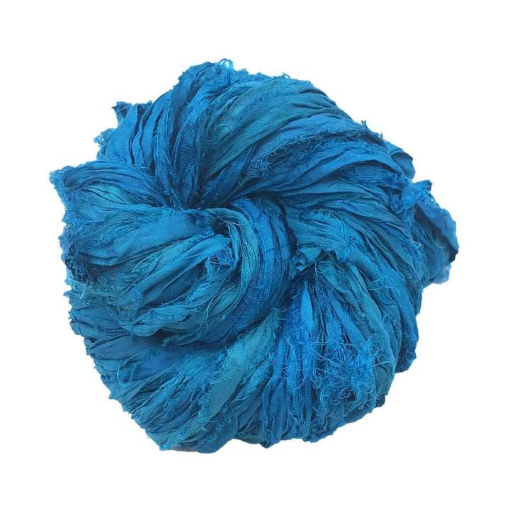 Single skein of sari silk ribbon yarn (medium blue) in front of a white background