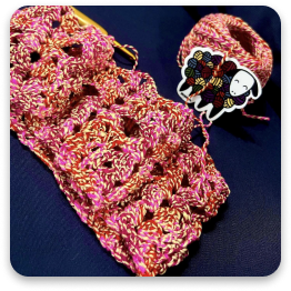 Crocheted pink and white square pattern with cartoon sticker.