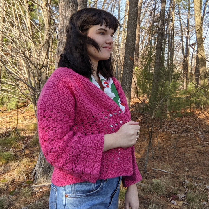 a person wearing a pink cardigan outside