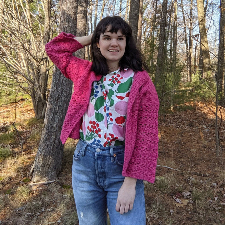a person wearing a pink cardigan outside