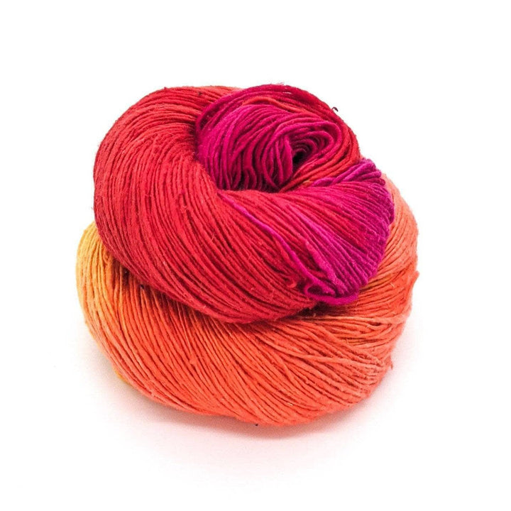 Lace weight silk yarn in color way color surge (orange, yellow and pink) in front of white background.