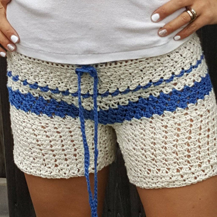 close up of a woman wearing white and blue crochet shorts 