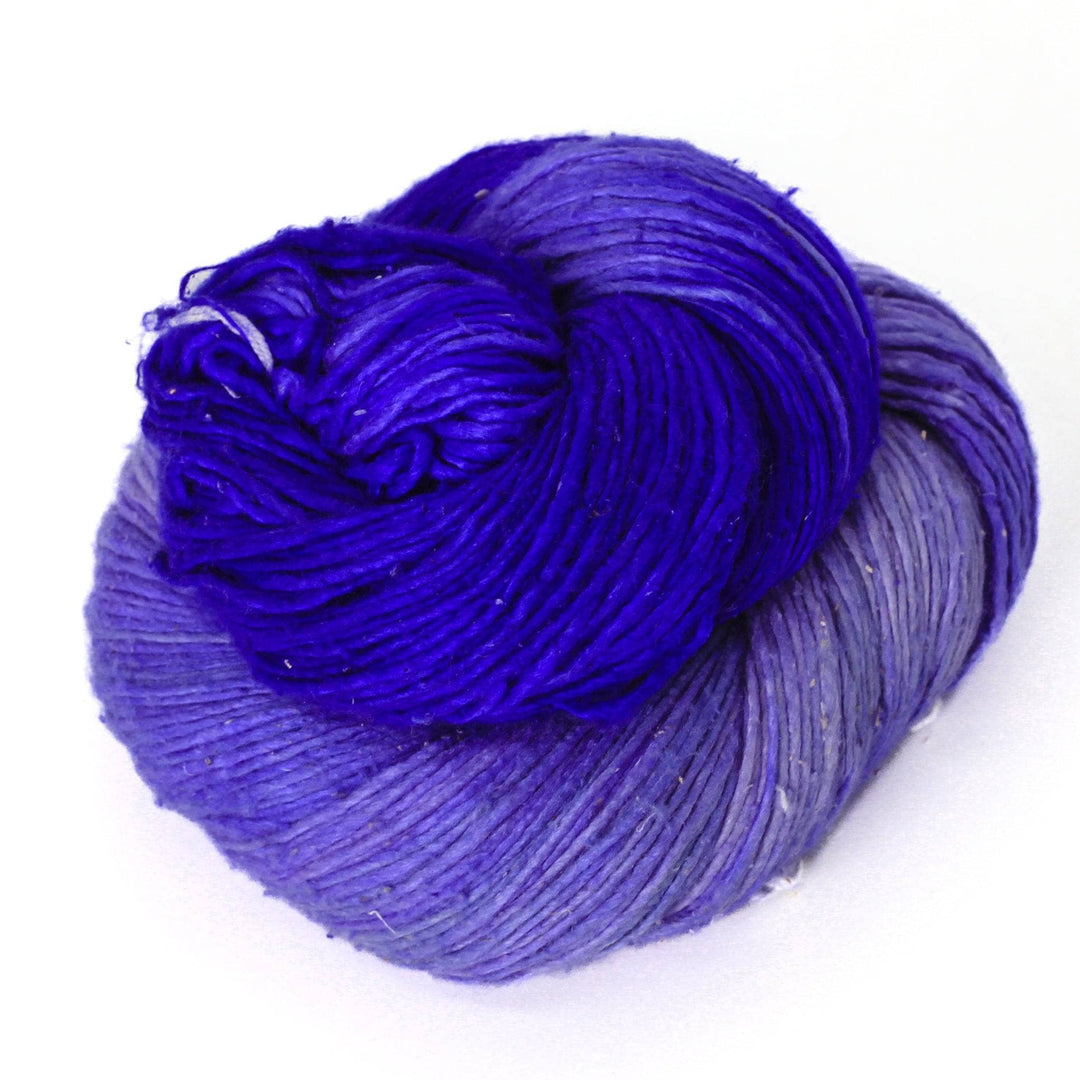 skein of variegated recycled silk yarn in purple in front of a white background.