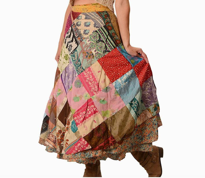 A person wearing a colorful patchwork skirt with various patterns and colors, including floral, stripes, and polka dots. The skirt is paired with brown boots.
