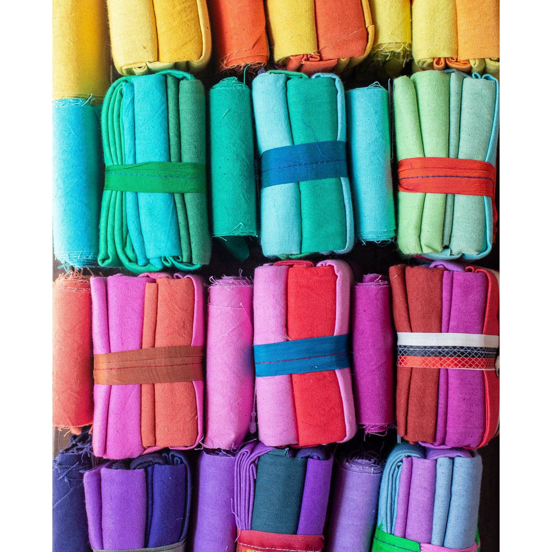 close up of 12 cotton fat quarter packs (top to bottom, yellows, blues, reds, and purples)