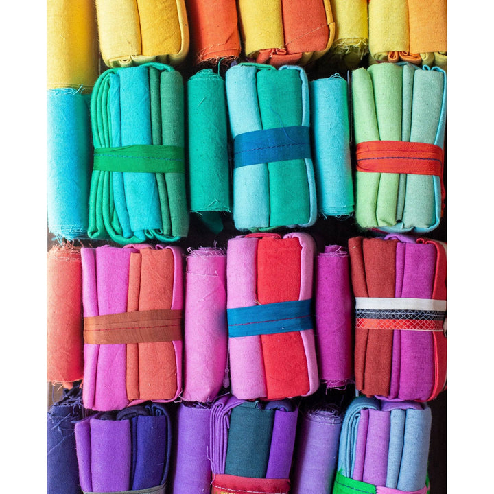 close up of 12 cotton fat quarter packs (top to bottom, yellows, blues, reds, and purples)