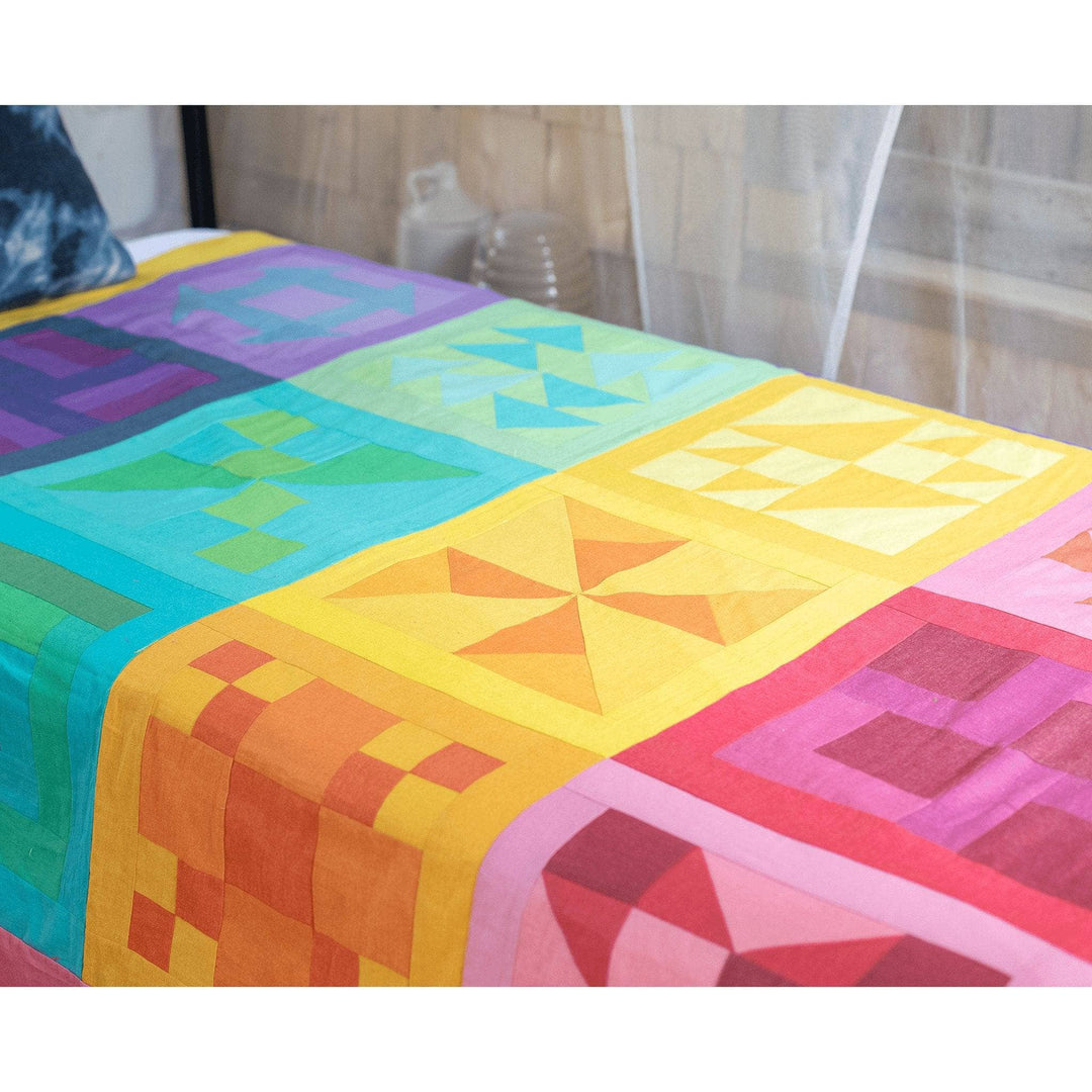 Rainbow Quilt completed laying on top of a twin size bed.