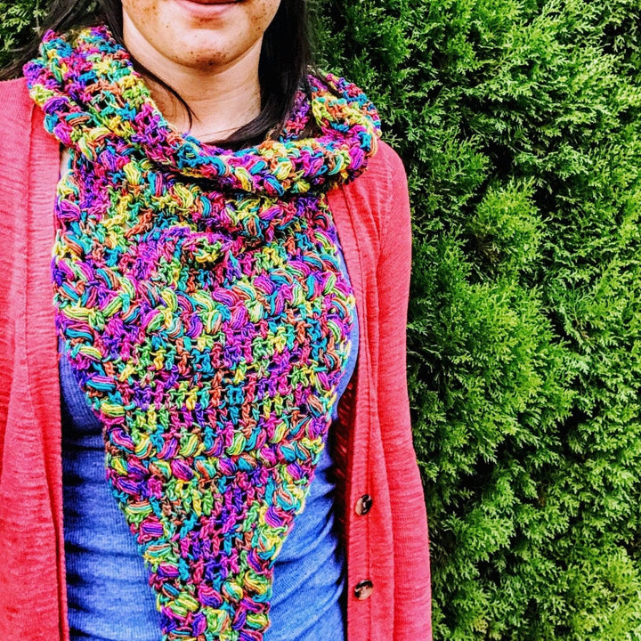 women wearing a rainbow cowl outside with trees in the background