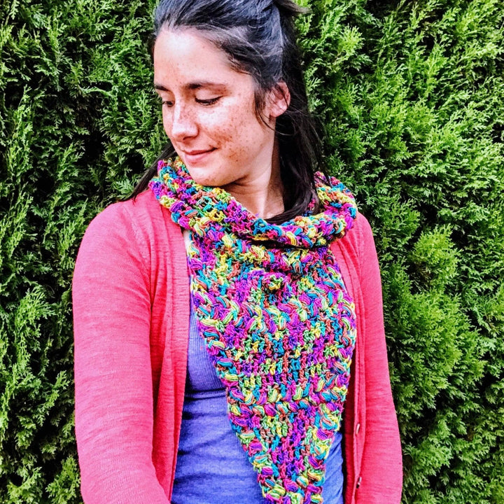 women wearing a rainbow cowl outside with trees in the background