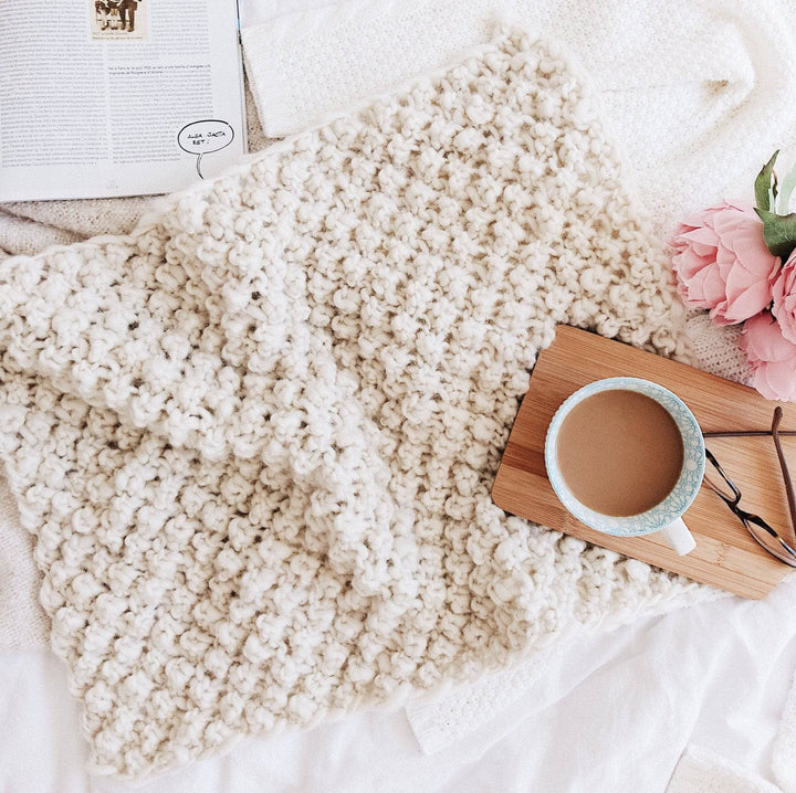 Raspberry Dream Baby Blanket with a mug of coffee and flowers on top of it