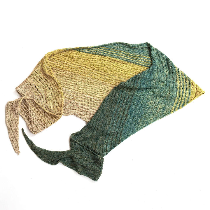 Ripple in the sand shawl folded in half laid flat in front of a white background. 