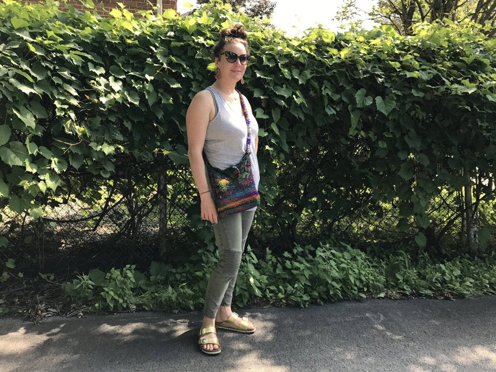 A woman smiling outside with a multicolored cross body purse on
