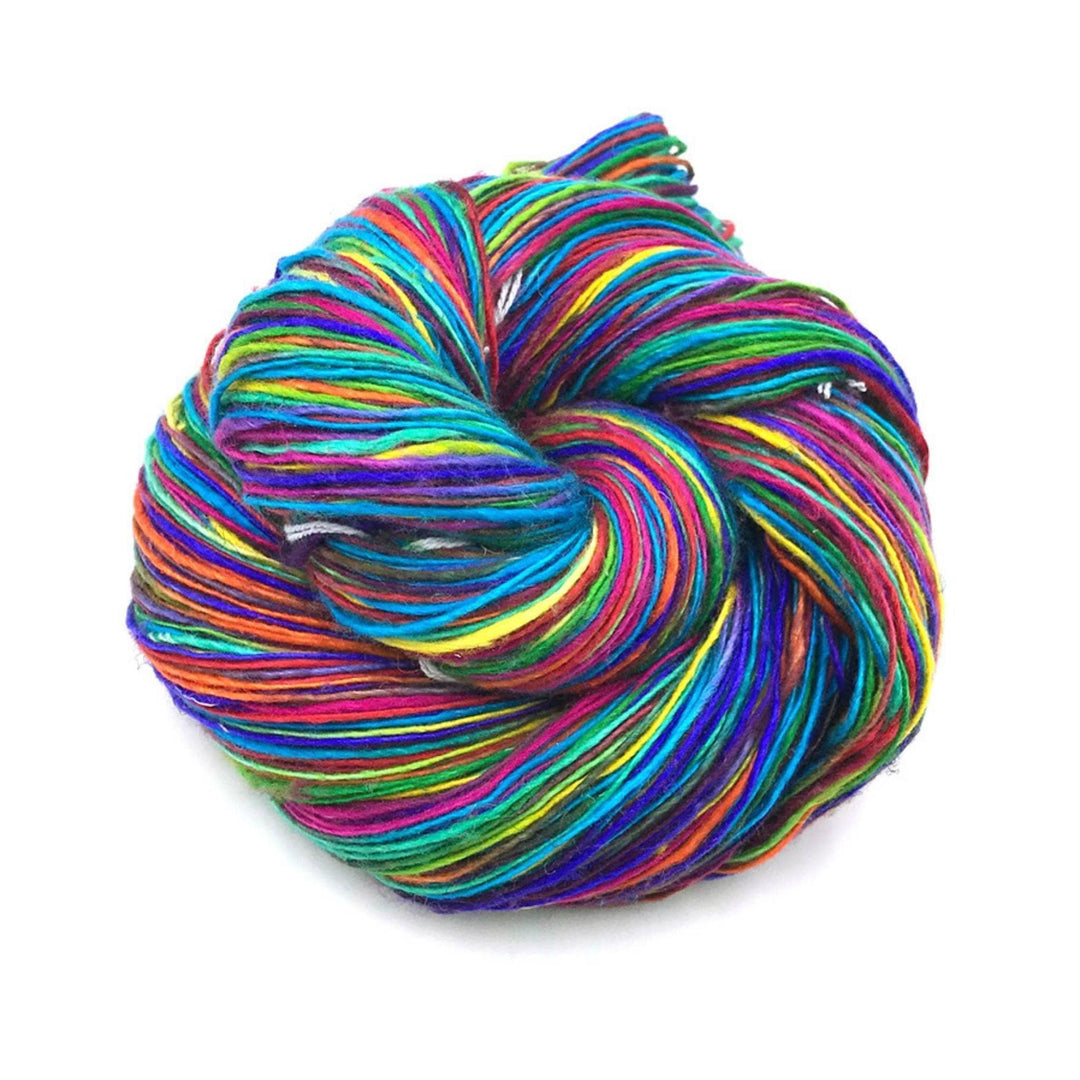 skein of vibrant variegated bright lace weight silk yarn in front of a white background. 