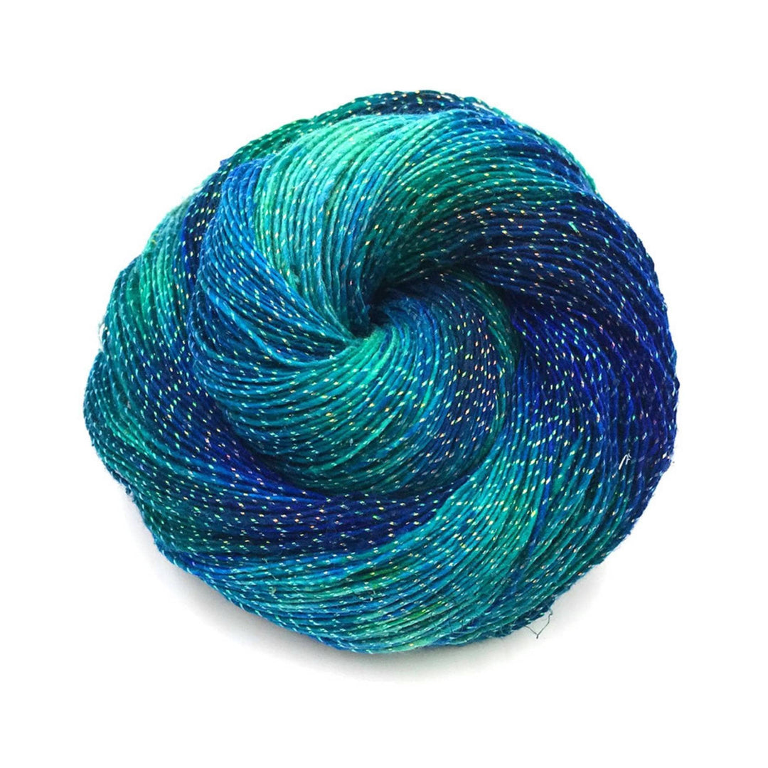 Skein of sparkle enchanted forest lace weight silk yarn in front of a white background. 
