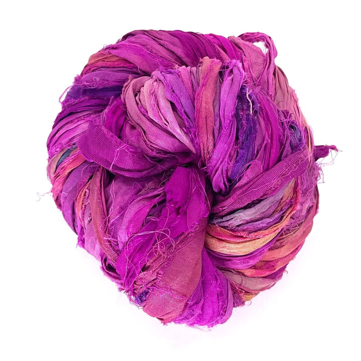 Ball of tightly wound multicolored fabric strips, mostly purple.
