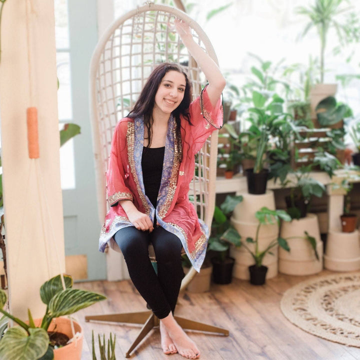A woman sitting on a hanging chair wearing sophia embellished silk duster.