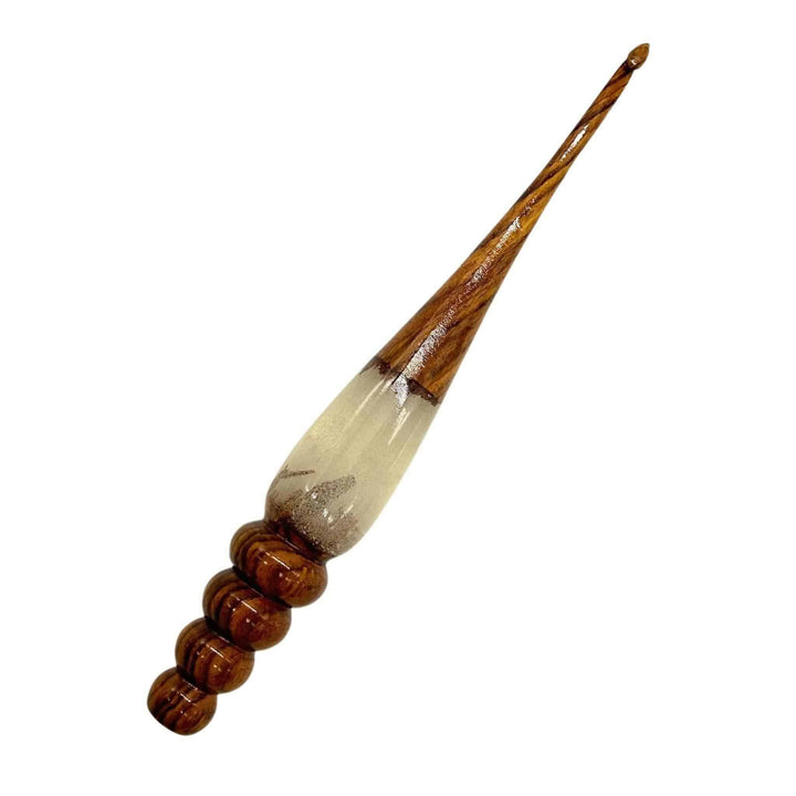 A woman's hand holing a  wooden and resin crochet hooks.