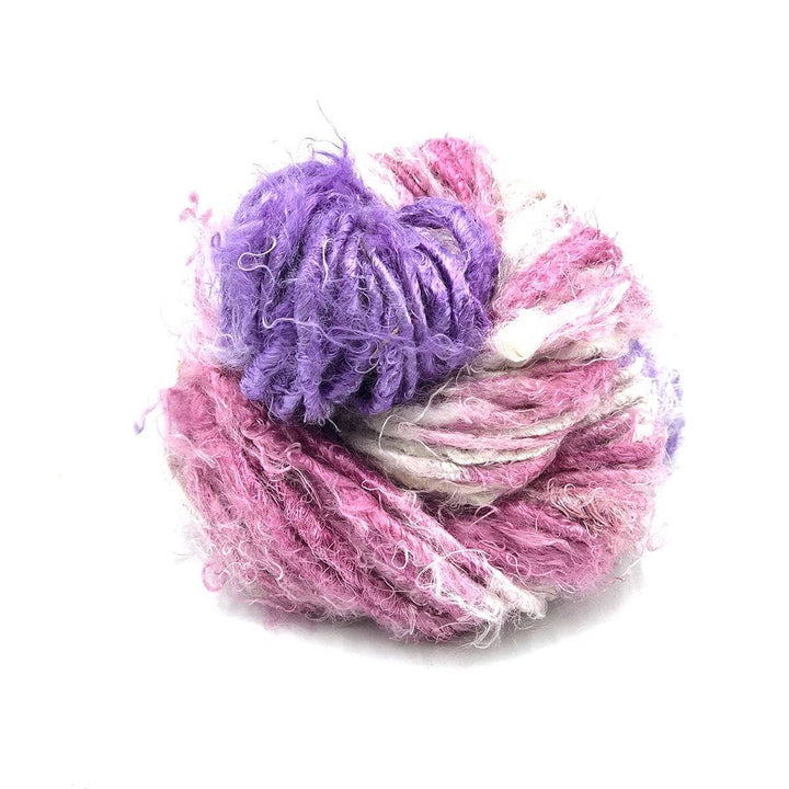 Banana fiber yarn donut ball in Mulberry Swirl (pink, purple, gray) on a white background