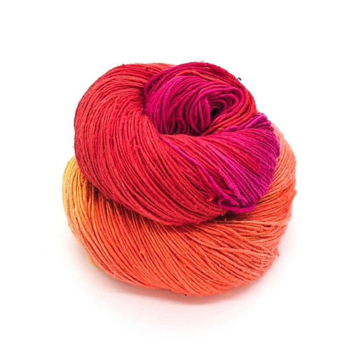 Lace weight silk yarn in color way color surge (orange, yellow and pink) in front of white background.