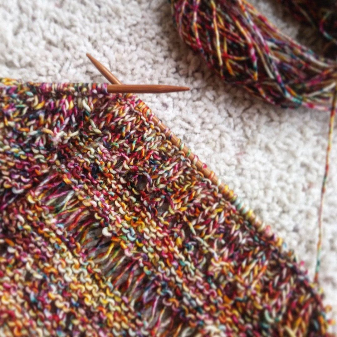 In progress picture of a yellow and red speckled shawl 