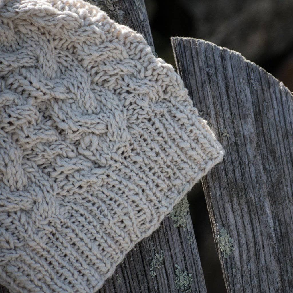 The Magnolia Beanie in Dandelion Poof (white) on a wooden background