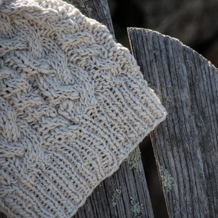 The Magnolia Beanie in Dandelion Poof (white) on a wooden background