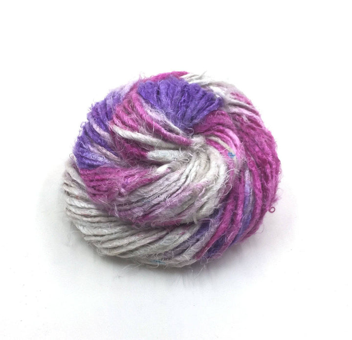 Banana fiber yarn donut ball in Mulberry Swirl (pink, purple, gray) on a white background
