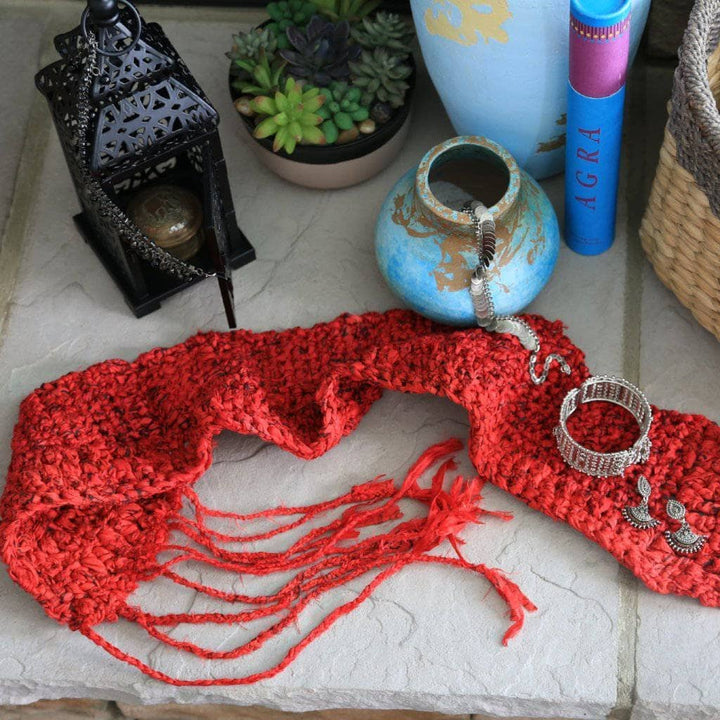 Red Taj Headscarf on a white surface next to pottery, a potted plant, and a basket