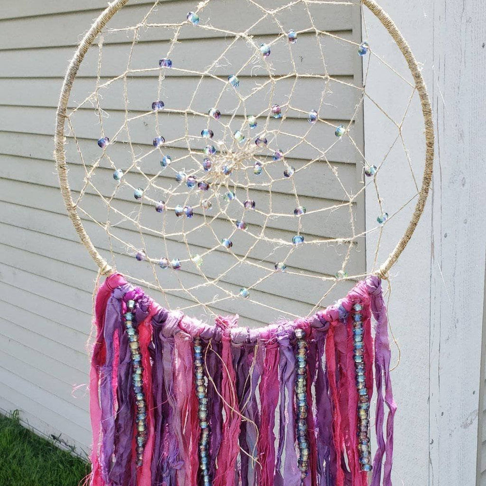 The Simple Dreamcatcher in pinks hung in front of a white wall