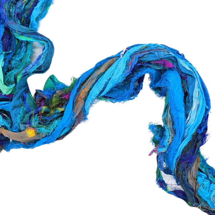 Untwisted skein of sari silk ribbon yarn turquoise in front of a white background to show detail.