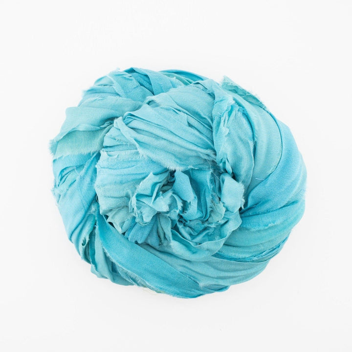 Light blue fabric crumpled into a circular shape on a plain white background.