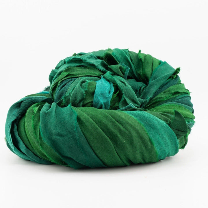 Large coiled bundle of green fabric with various shades and textures on a white background.