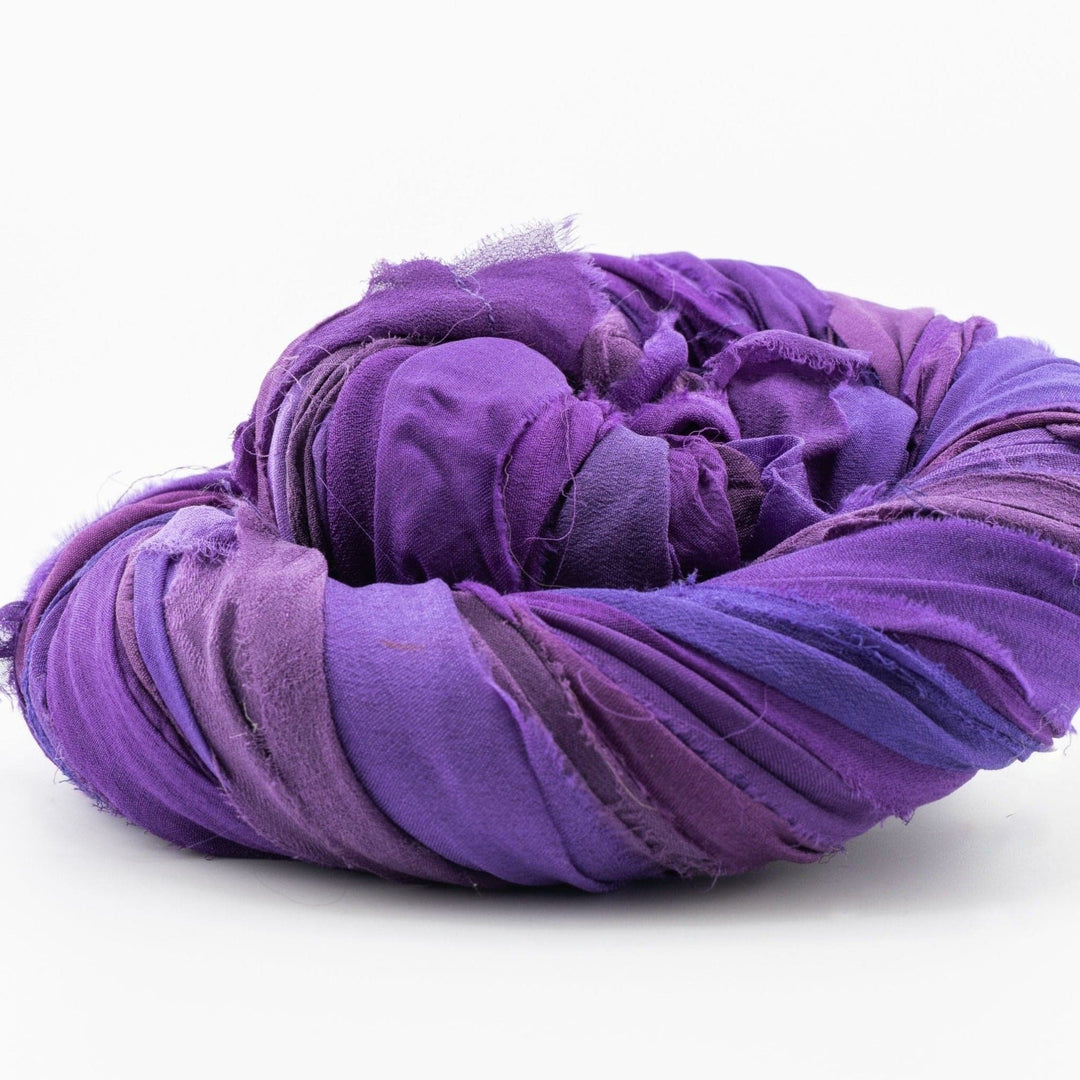 A coiled bundle of fabric strips in varying shades of purple on a white background.