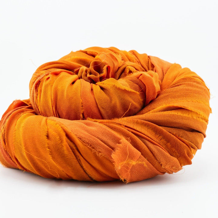 Orange fabric rolled into a circular shape against a white background.