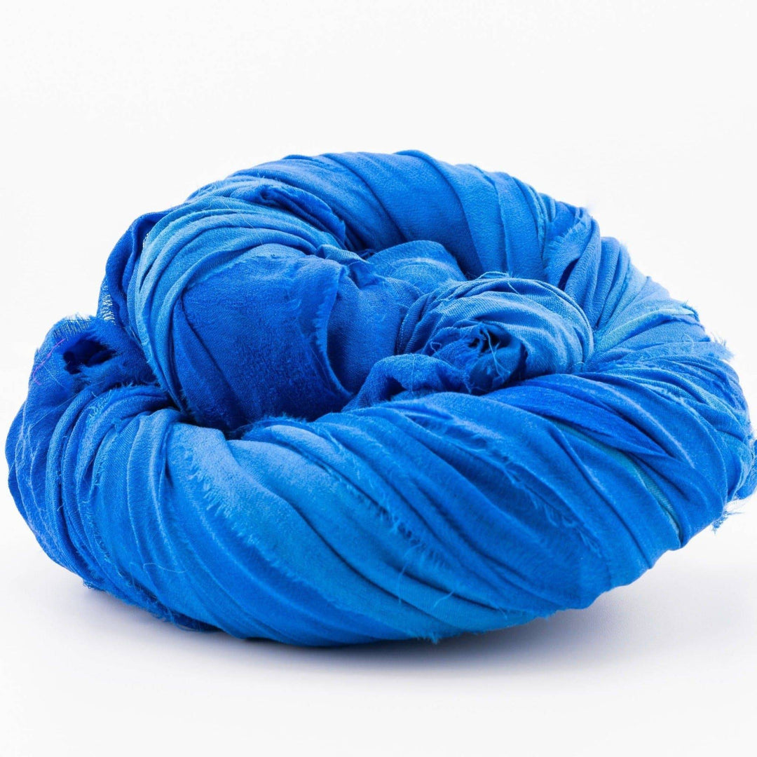 Coiled bright blue fabric piece on a white surface.