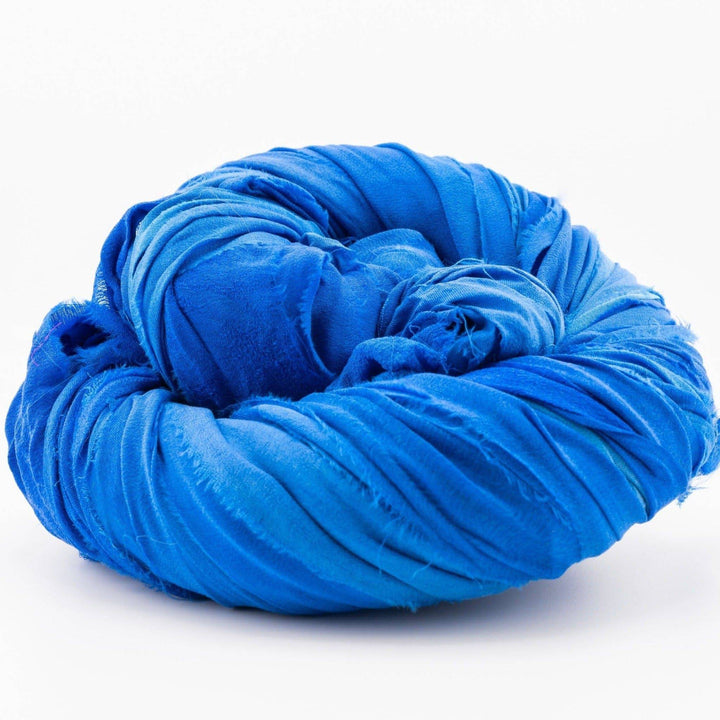 Coiled bright blue fabric piece on a white surface.
