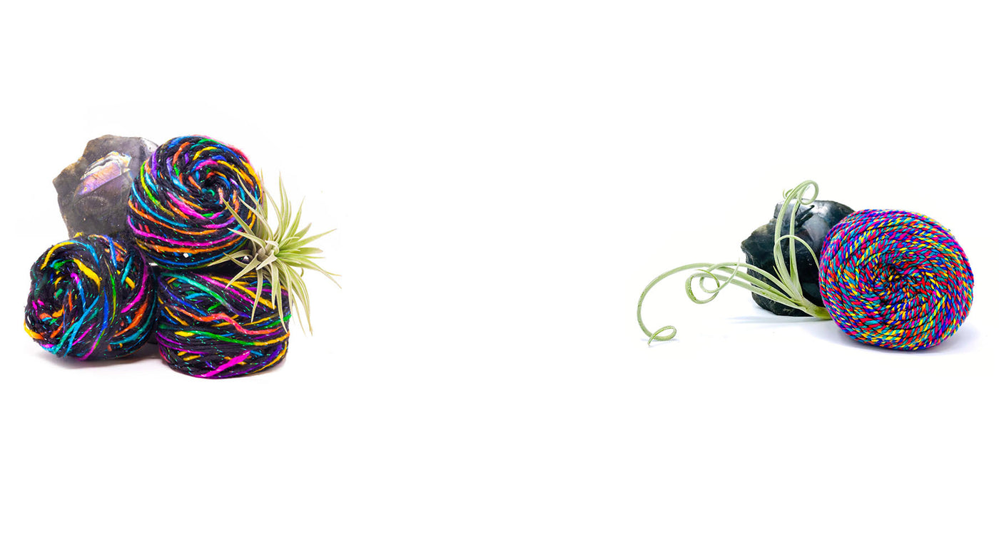 Four brightly colored skeins of Yarn of the Month on white background with natural green and stone props.