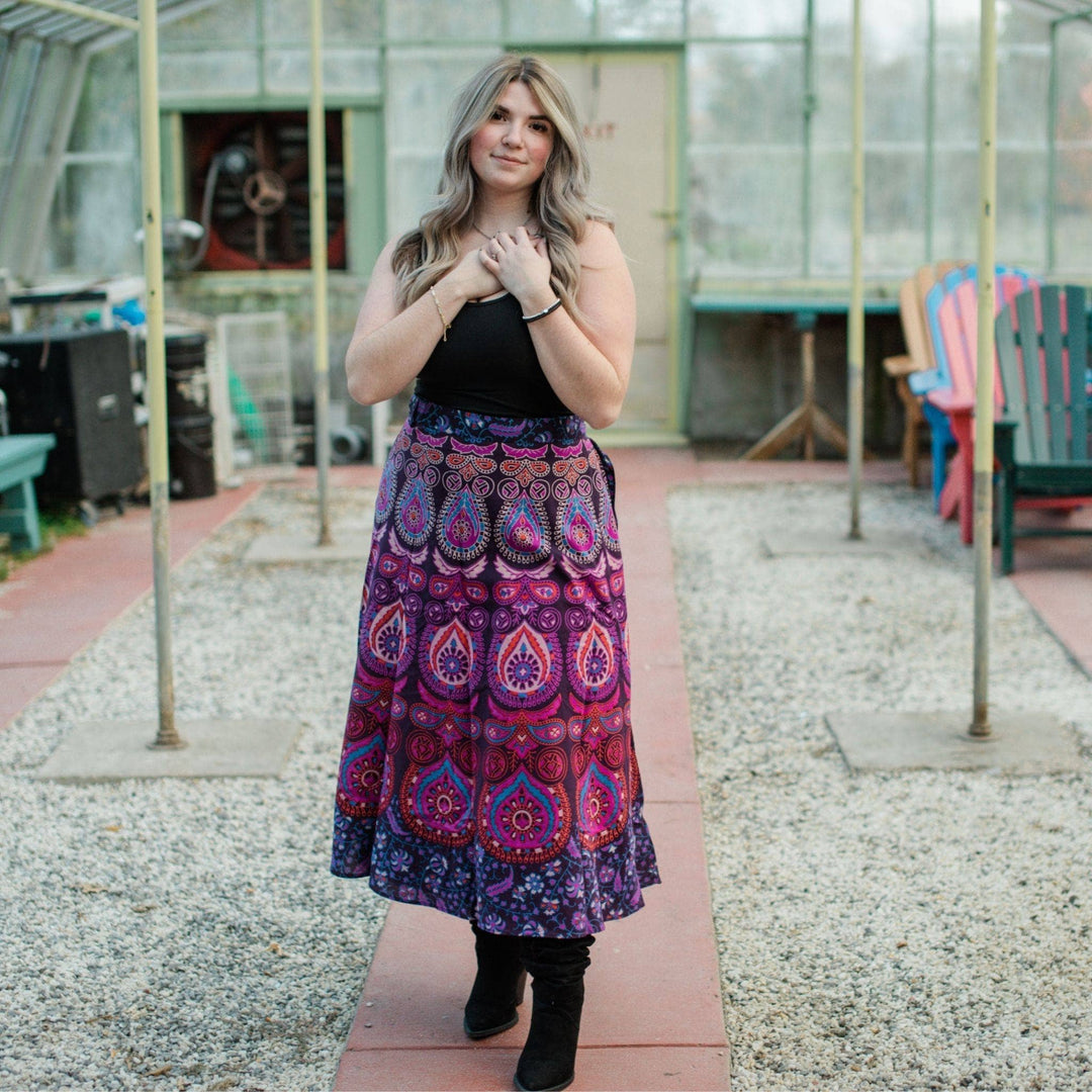 Model wearing purple cotton wrap skirt while standing in a greenhouse.