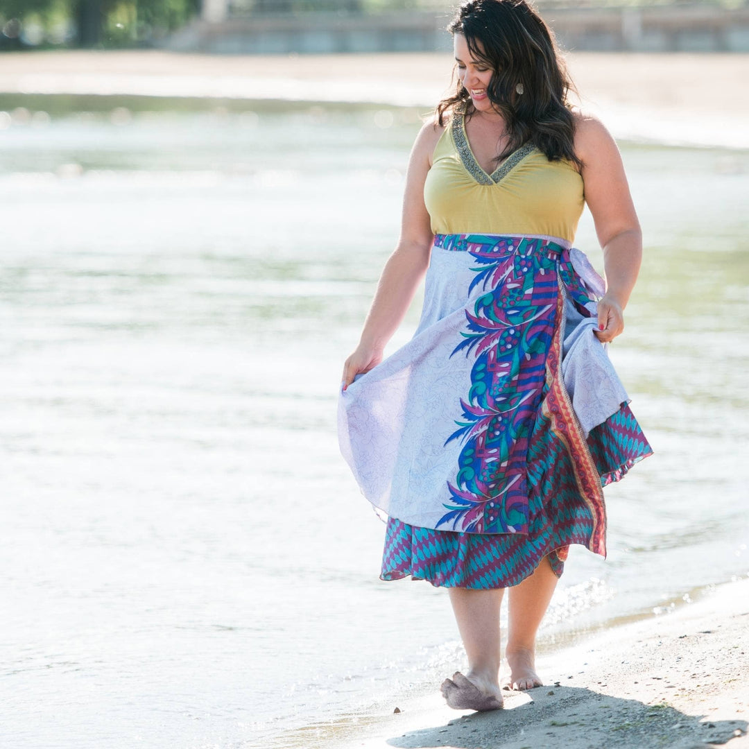 Model is wearing a plus size maxi sari silk wrap skirt while walking on the beach.